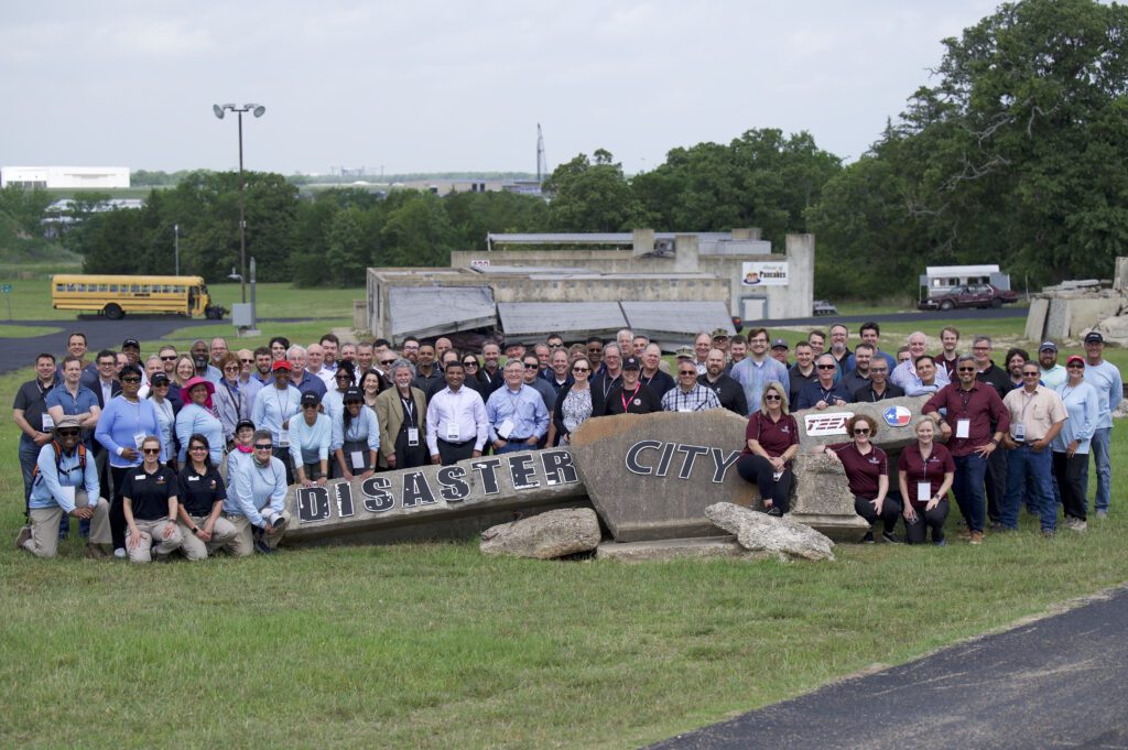 interoperability institute 2024 attendees around disaster city sign