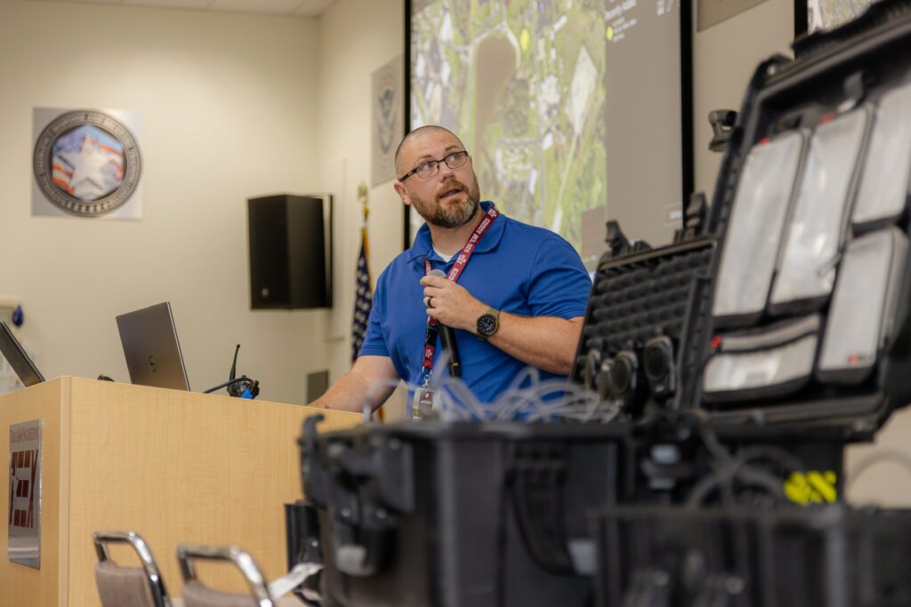 Speaker presenting next to equipment at interoperability institute 2024